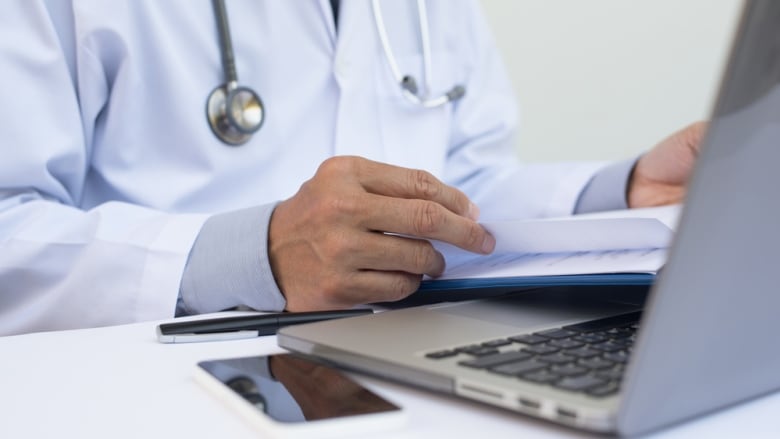 A stock image of a physician sitting at a lap computer.