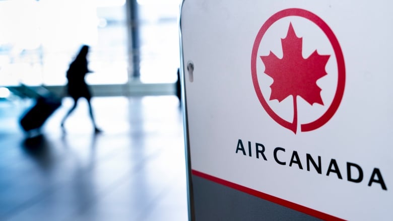 A sign reading 'Air Canada' with a person in silhouette behind it.