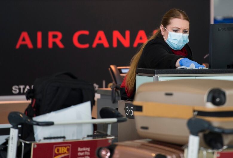 An Air Canada worker cleans her ticketing station at Pearson International Airport in Toronto on Wednesday, April 8, 2020.