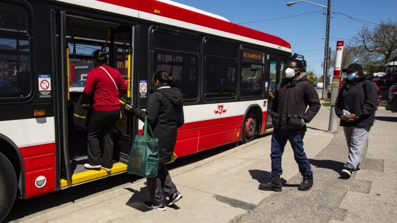 People wait to get on a TTC bus.