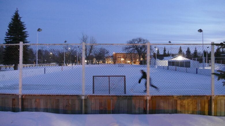 A person plays hockey on an outdoor skating rink.