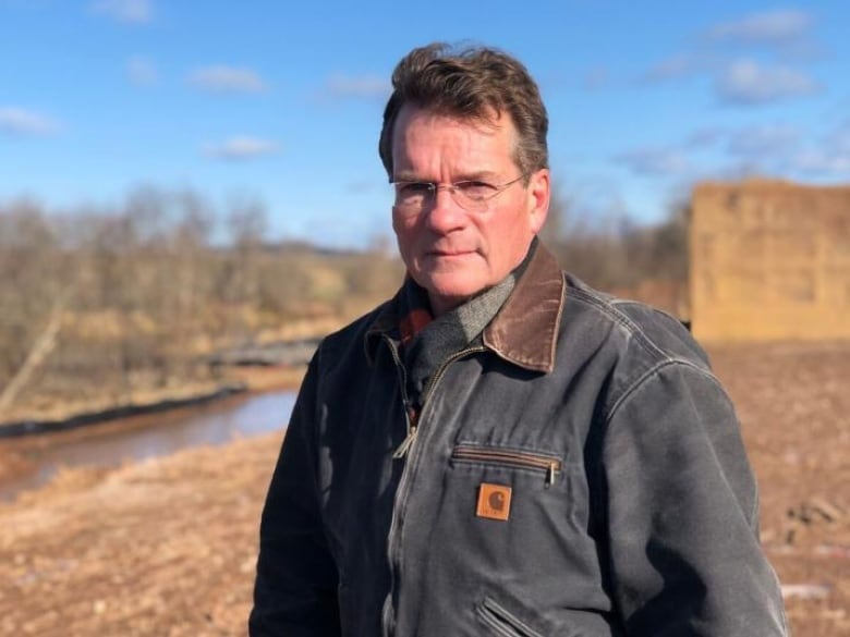 An unsmiling man standing outside wearing a Carhartt jacket