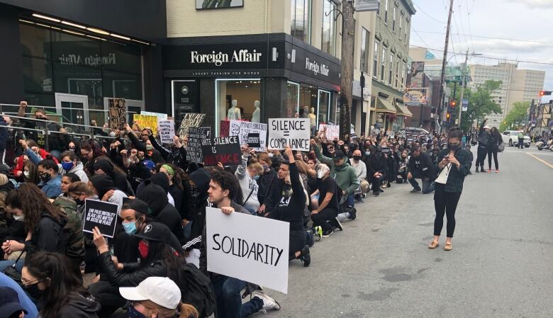 Demonstrators take a knee on Spring Garden Road in Halifax to protest the death of George Floyd.