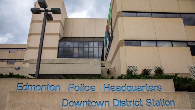 A large concrete building with black windows is shown. A sign on the property reads, Edmonton Police Headquarters, Downtown District Station. 