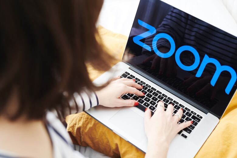 A woman uses the Zoom messaging app on a laptop.