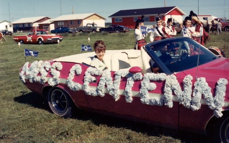 A woman rides in a convertible.