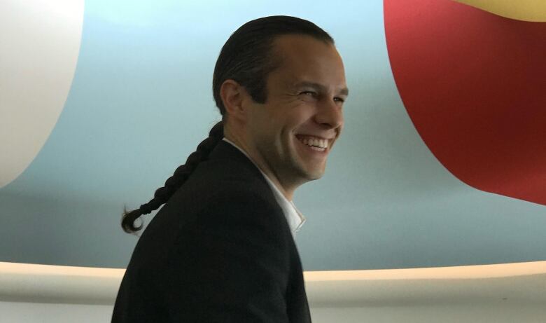 A man wearing a suit smiles for the camera towards the right frame.