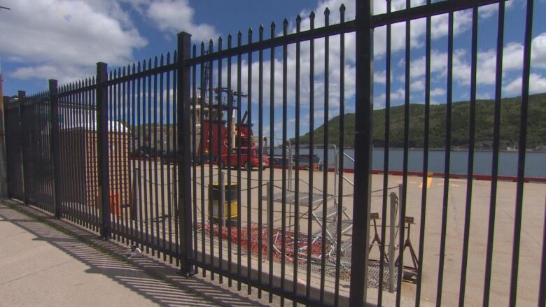 The tall black poles of the harbor fence restrict the view of the St. John's harbor.