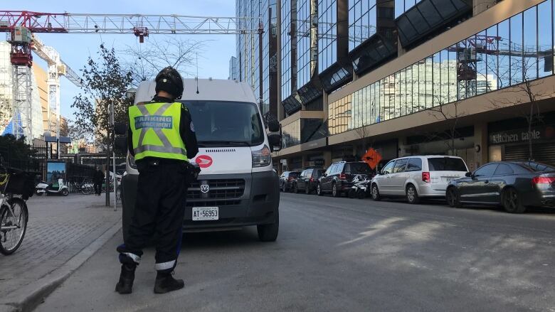 A Toronto police parking enforcement officer issues a ticket on Edward Street, north of Yonge-Dundas Square.