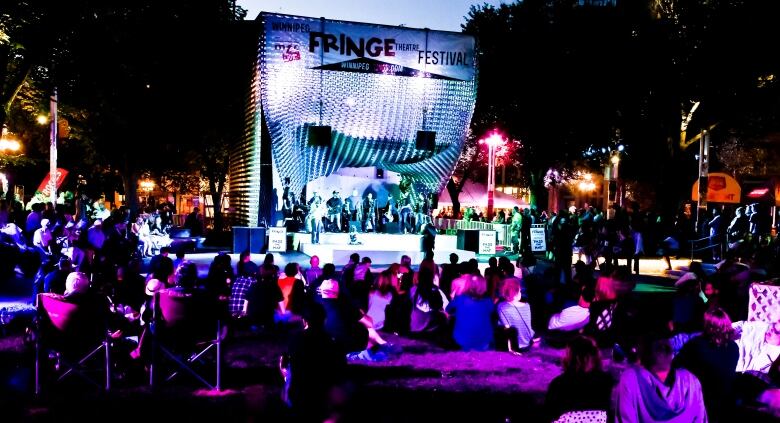 A crowd is pictured watching musical acts perform on stage at night.