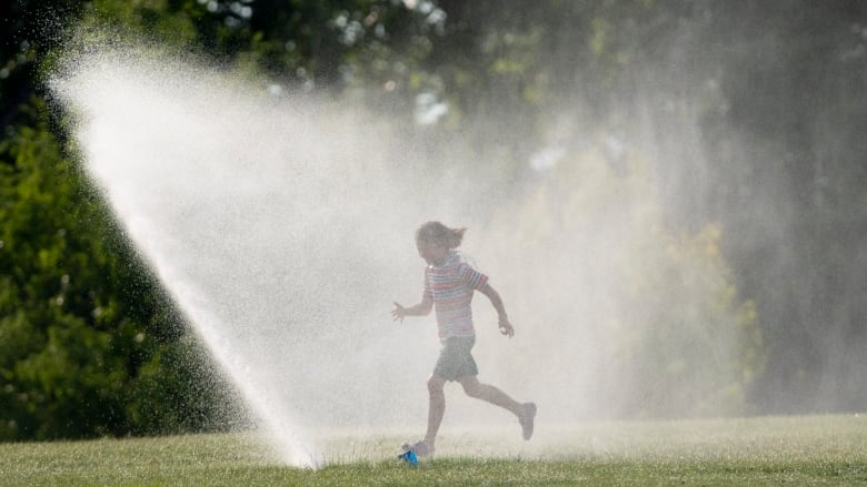 A person runs through a sprinkler.