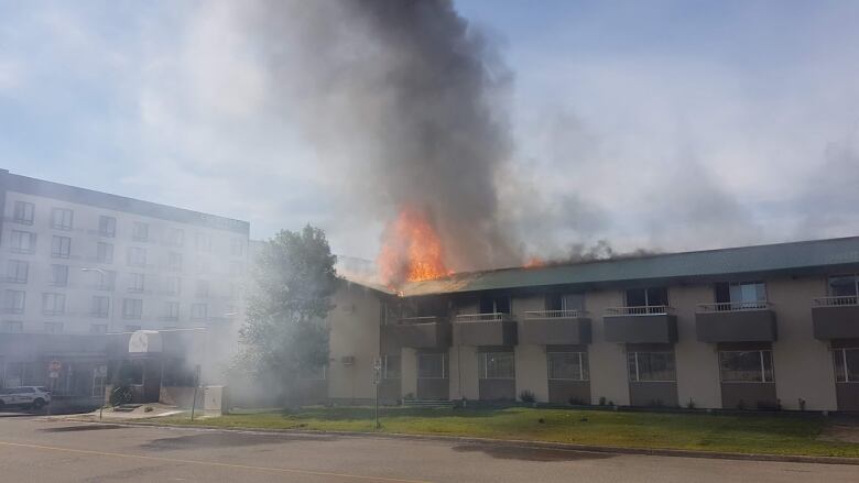 Orange flames are seen shooting out the roof of an old motel.