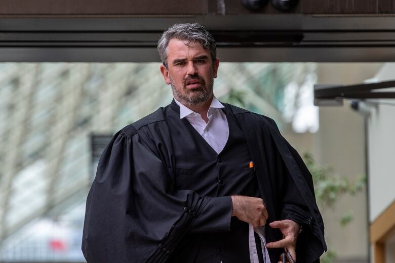 A lawyer in robes walks outside.