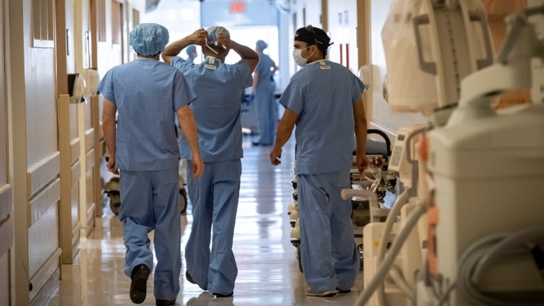 Surgical oncologists Dr. Usmaan Hameed, right, and Dr. Peter Stotland, left, walk to the operating room at North York General Hospital on May 26, 2020.