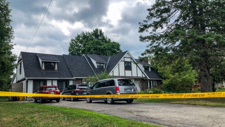 A rural home in summer with caution tape in front of it.