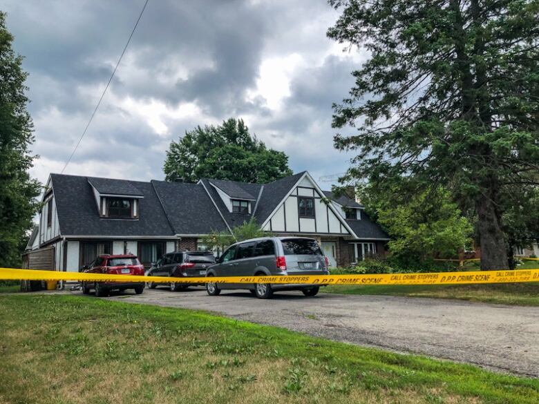 A rural home in summer with caution tape in front of it.