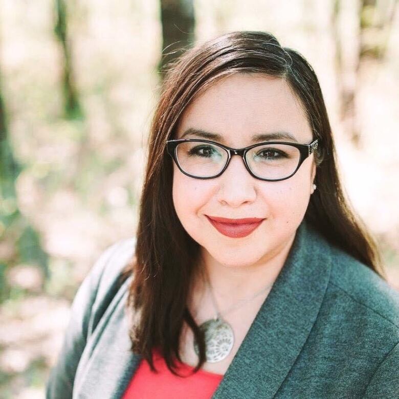 A woman with glasses poses for a portrait.