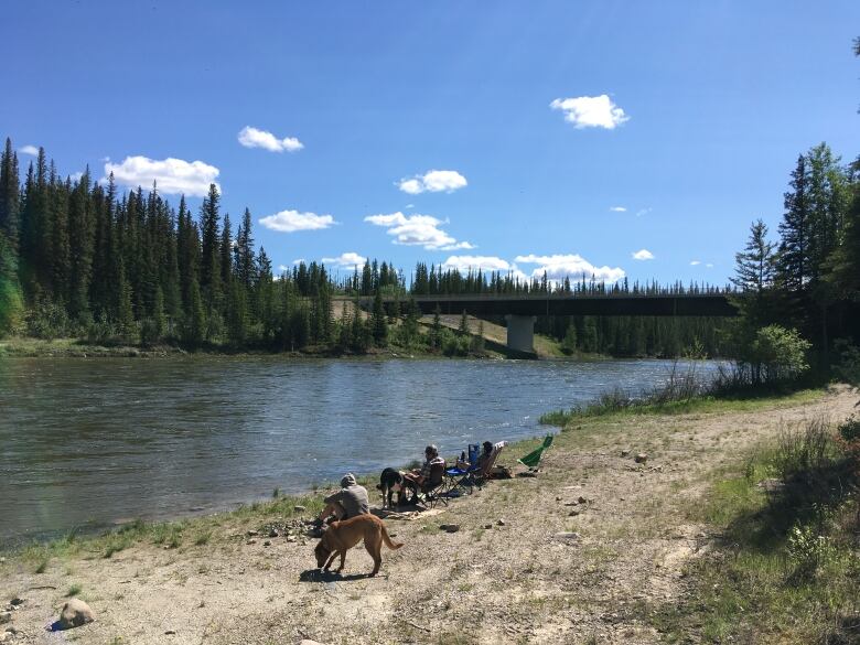 People sit along the edge of a river.