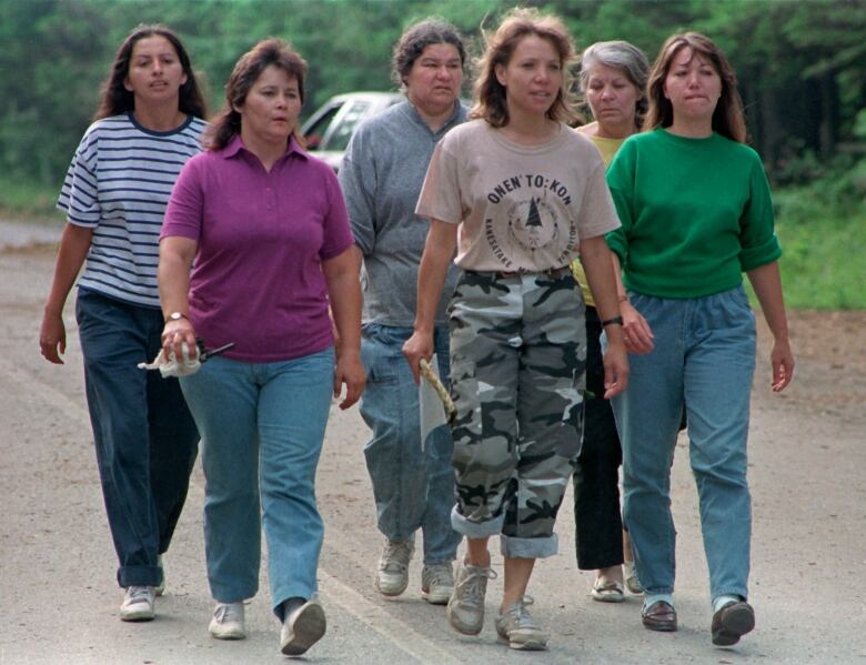 Six women walk down a road in the '90s.