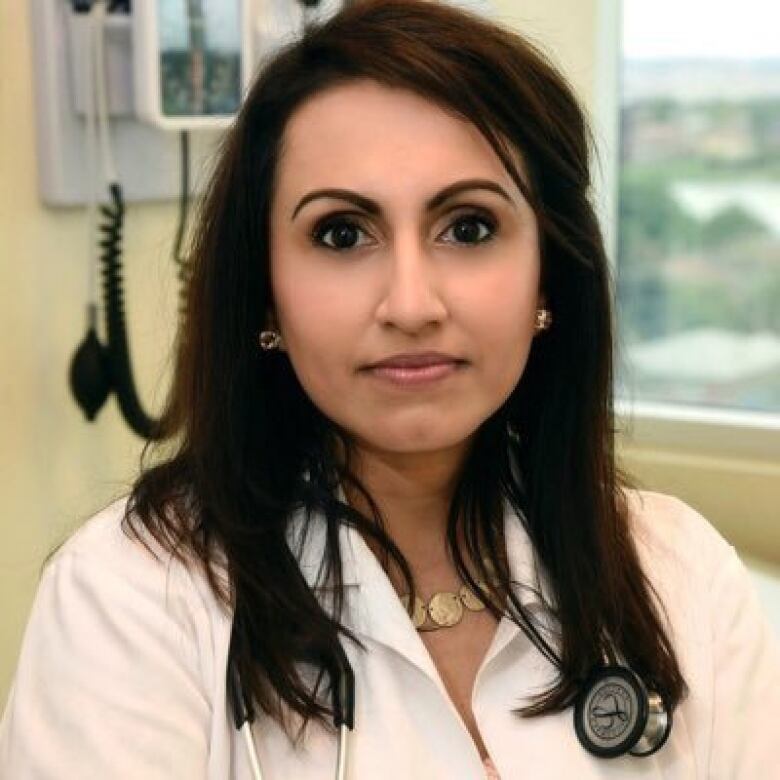 A woman in a white lab coat and a stethoscope around her neck at a clinic.