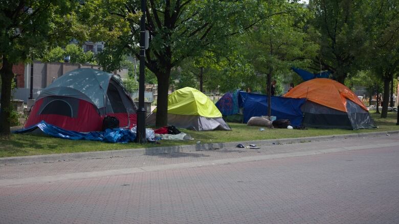 A series of tents lines a boulevard on a city street in Hamilton