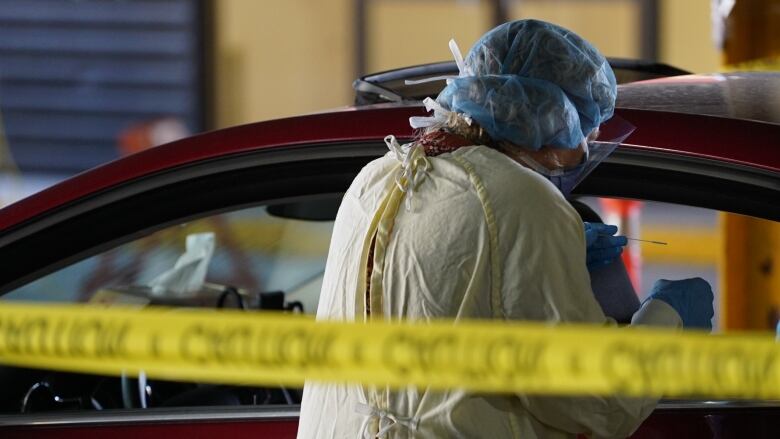 A person being tested for COVID in their car is shown.