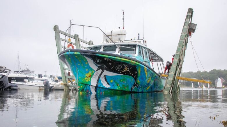 A colourful fishing boat tied up at a wharf 