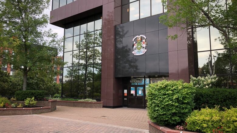 A brick-and-glass building is shown with a large crest mounted on the wall over an entrance labelled 'city hall.'