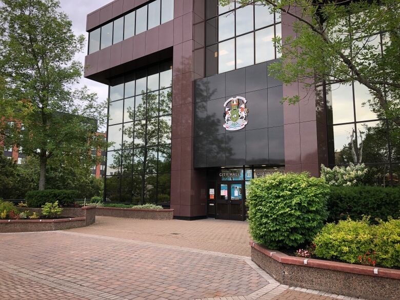 A brick-and-glass building is shown with a large crest mounted on the wall over an entrance labelled 'city hall.'