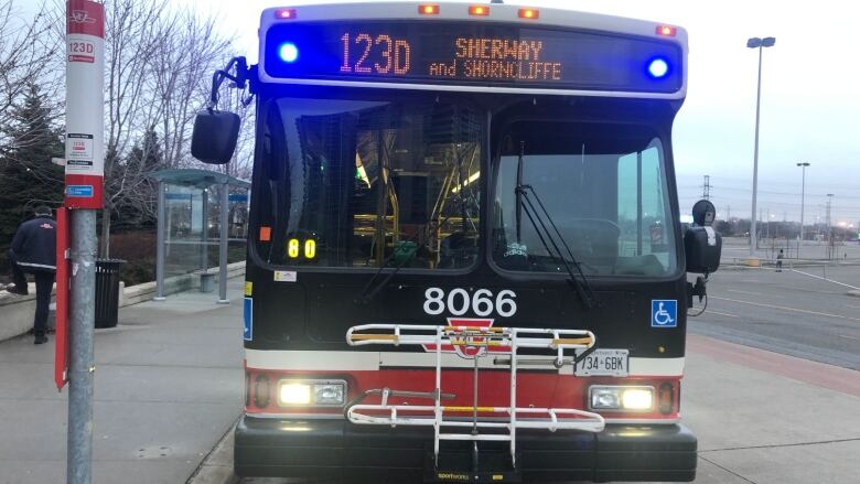 A TTC bus at a stop on an overcast day.