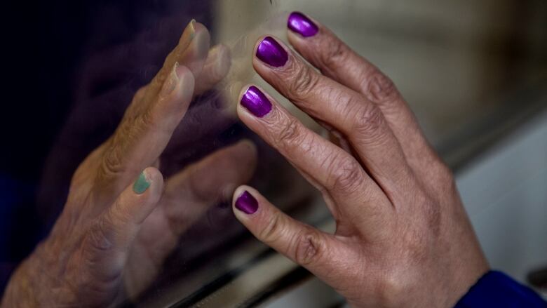 Two hand both touching against a piece of glass between them