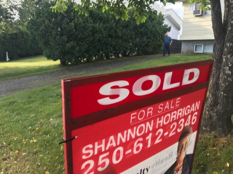 A 'SOLD' realtor sign outside a large house.