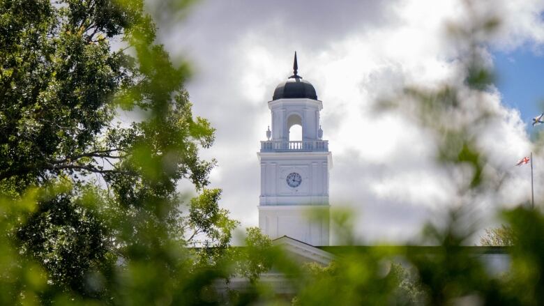 A white bell tower framed by green trees.