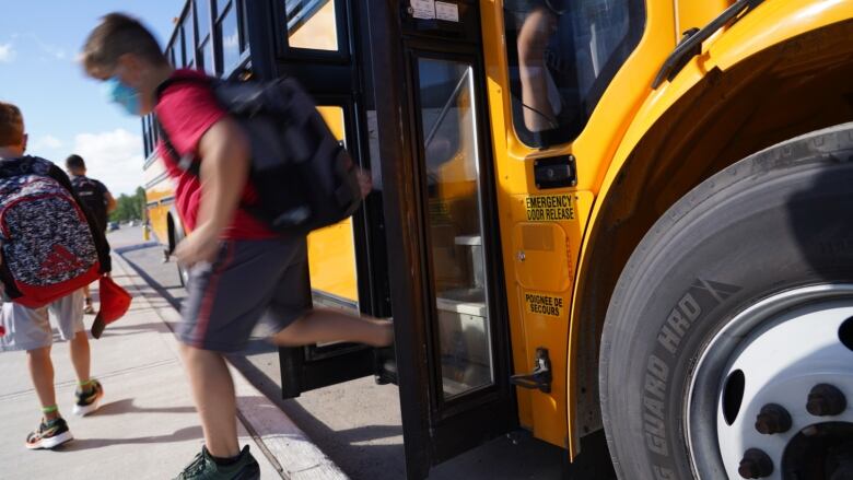 Child walking off the stairs of a school bus. 