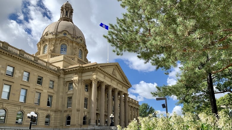 A sandstone public building is seen from a wide angle