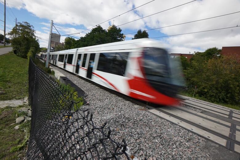 A red and white train speeds along a rail line.