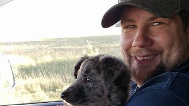 A man poses with a dog in a car.