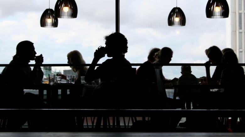 Silhouetted figures are shown dining in a restaurant.