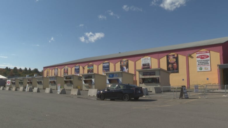 A row of food vendor huts affronts a large rectangular building.