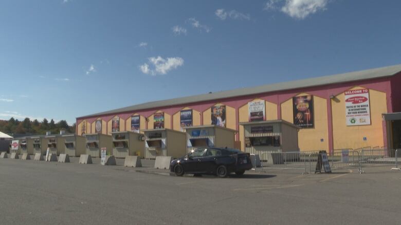 A row of food vendor huts affronts a large rectangular building.