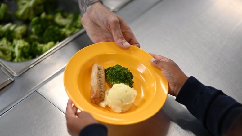 A school chef serves cooked hot dinner to students on their lunch break at St Luke's Church of England Primary School in East London on September 3, 2020. - Pupils in Britain have on Thursday begun to return to schools for the first time since they were all closed in March, due to the COVID-19 pandemic. (Photo by DANIEL LEAL-OLIVAS / AFP) (Photo by DANIEL LEAL-OLIVAS/AFP via Getty Images)