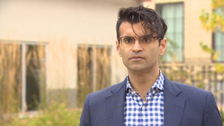 A closeup of a lawyer wearing glasses and a blue jacket.