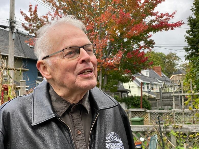 An older man with white hair and glasses looks off camera. 