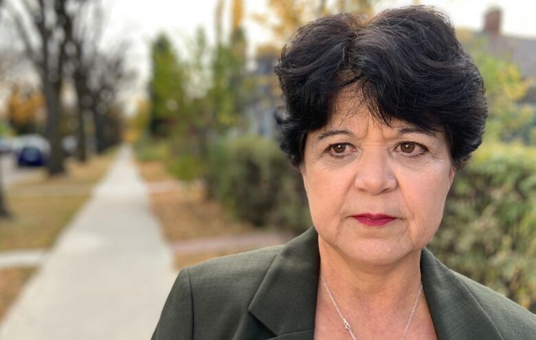 Sandra Azocar has short dark brown hair. She's standing on a sidewalk