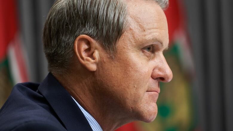 A tight shot of the side of Cameron Friesen's face. The background shows blurred flags.