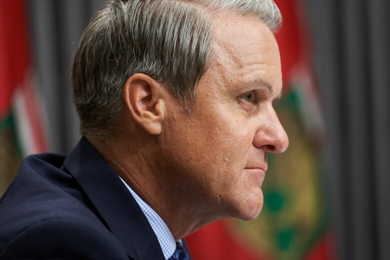 A tight shot of the side of Cameron Friesen's face. The background shows blurred flags.