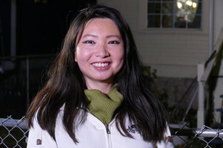 A woman wearing a white jacket smiles for a photo. 