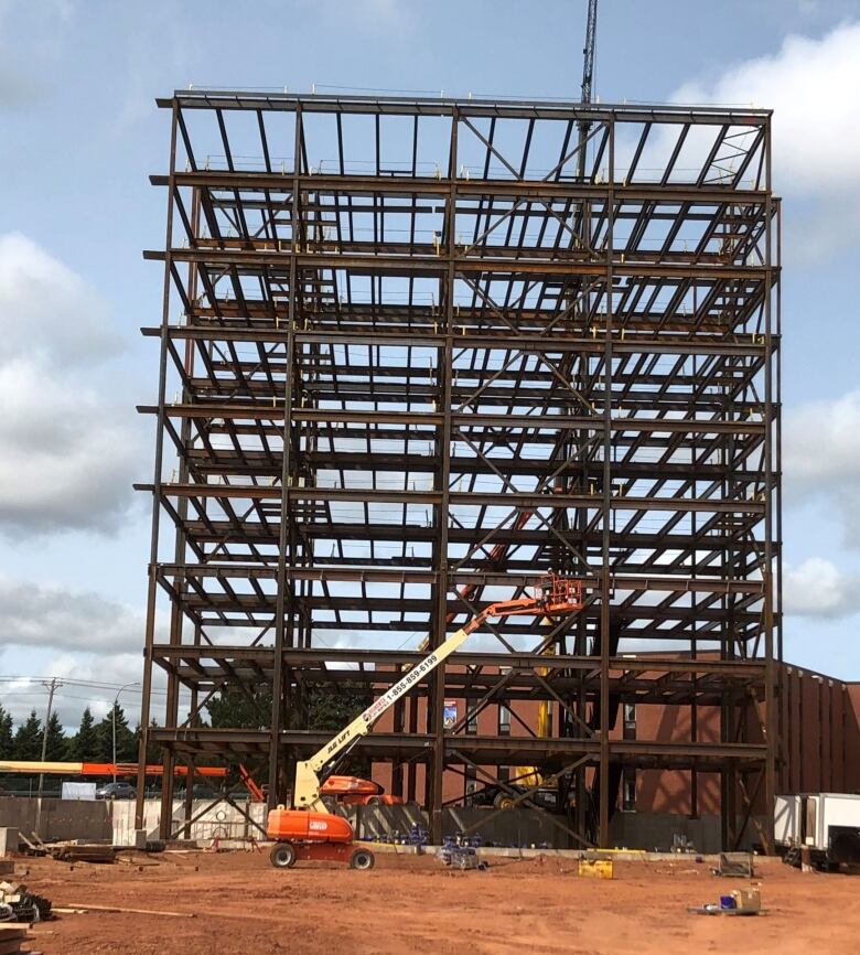 A steel-girdered building under construction with crane in the foreground.