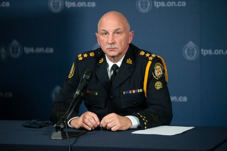 A man in a police uniform sitting behind a microphone.