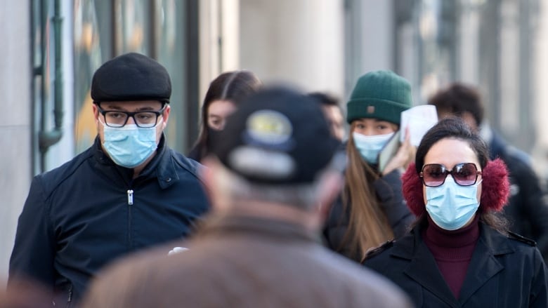 People in masks are pictured walking in Quebec.